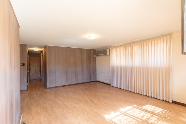 spare room with wooden walls, light hardwood / wood-style floors, and a wall unit AC