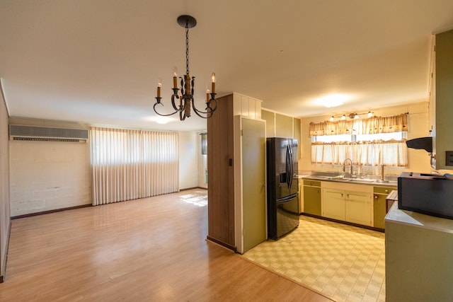 kitchen featuring decorative light fixtures, black fridge with ice dispenser, dishwasher, light hardwood / wood-style flooring, and sink