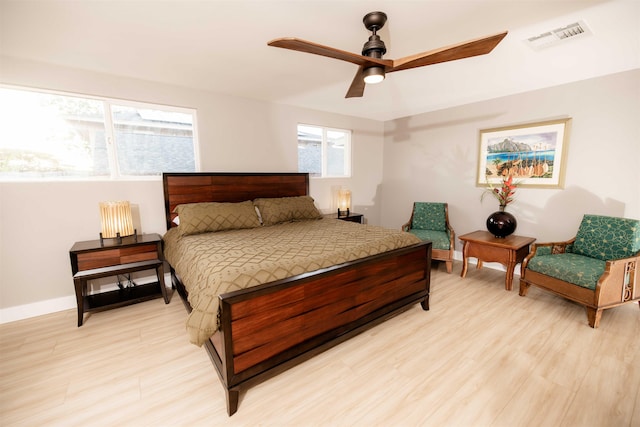 bedroom featuring ceiling fan, light wood finished floors, visible vents, and baseboards