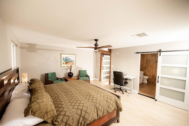 bedroom featuring a barn door, baseboards, visible vents, a ceiling fan, and light wood-type flooring