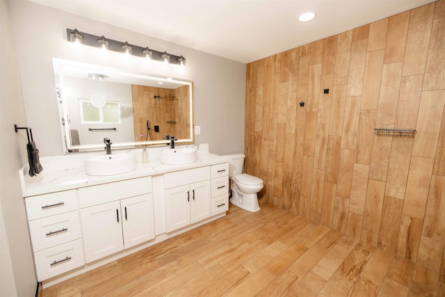 bathroom with a sink, a tile shower, toilet, and double vanity