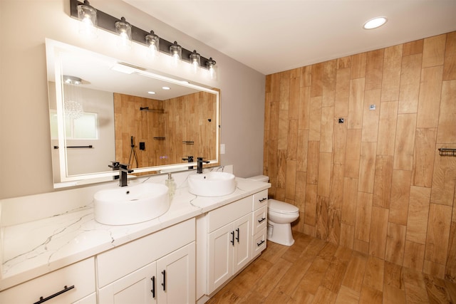 bathroom featuring double vanity, toilet, a sink, and tiled shower