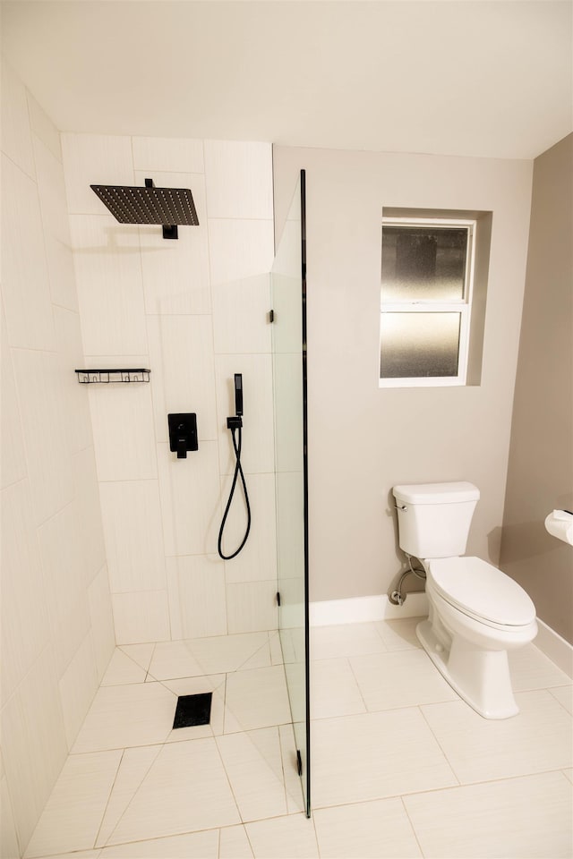 bathroom featuring tiled shower, tile patterned flooring, toilet, and baseboards