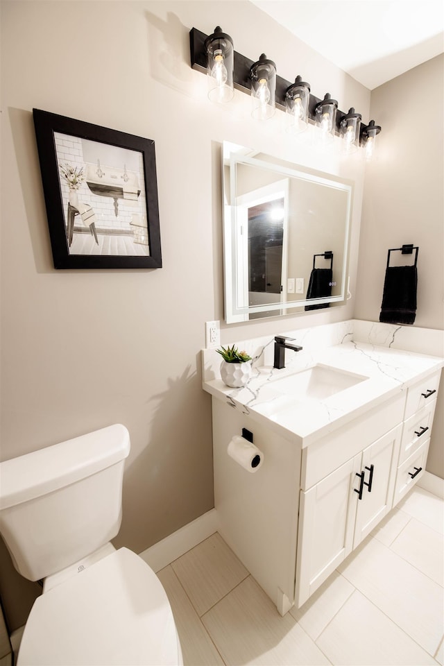 bathroom with tile patterned flooring, vanity, toilet, and baseboards