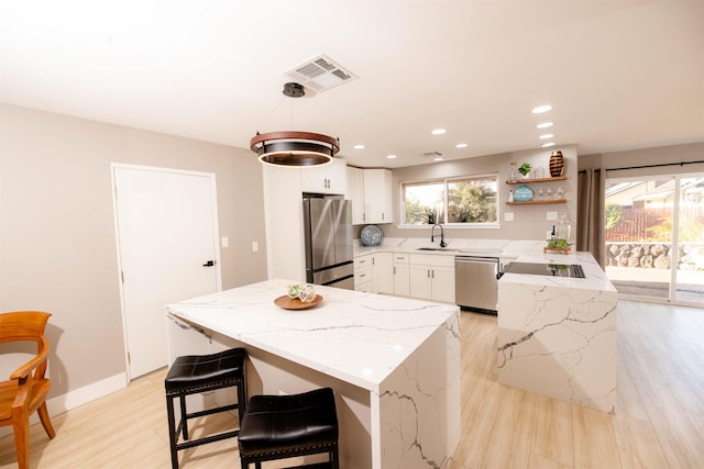 kitchen with stainless steel appliances, a peninsula, a sink, visible vents, and light stone countertops