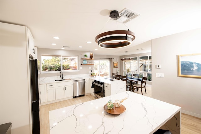 kitchen with wall oven, freestanding refrigerator, a sink, dishwasher, and a peninsula