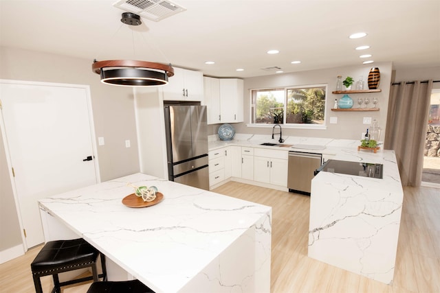 kitchen featuring visible vents, appliances with stainless steel finishes, white cabinetry, a sink, and light stone countertops