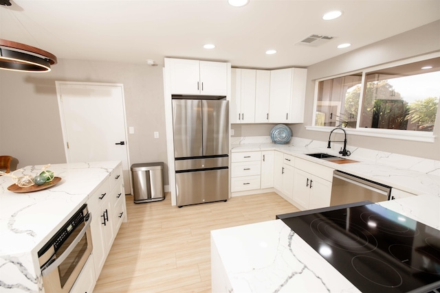 kitchen featuring visible vents, appliances with stainless steel finishes, light stone counters, white cabinetry, and a sink