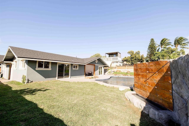 back of house with a shingled roof, a lawn, a patio, fence, and stucco siding