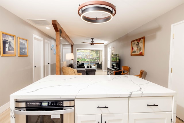 kitchen with light stone countertops, open floor plan, visible vents, and white cabinetry