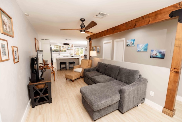 living area featuring baseboards, light wood finished floors, visible vents, and a ceiling fan