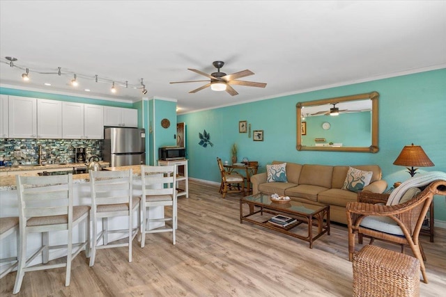 kitchen featuring white cabinetry, stainless steel appliances, decorative backsplash, light stone countertops, and ornamental molding