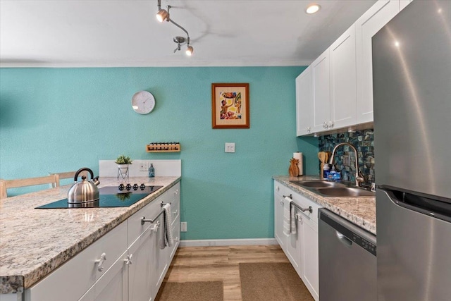 kitchen with stainless steel appliances, decorative backsplash, white cabinets, light hardwood / wood-style flooring, and sink