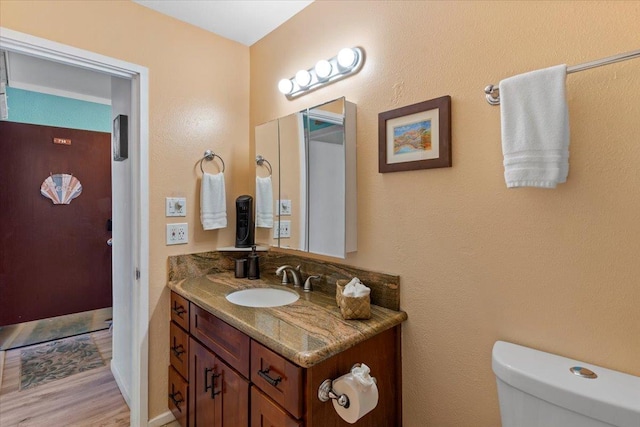 bathroom with toilet, hardwood / wood-style flooring, and vanity