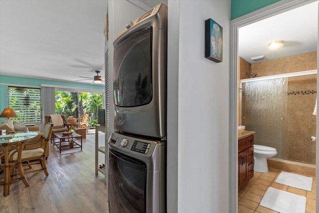 laundry room featuring ceiling fan, stacked washer and dryer, and light tile patterned flooring