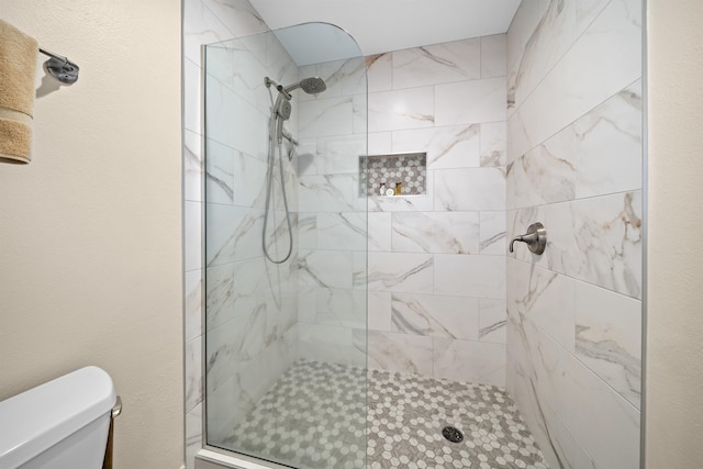 bathroom with tiled shower and toilet