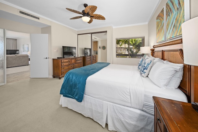 bedroom with light colored carpet, ornamental molding, a closet, and ceiling fan