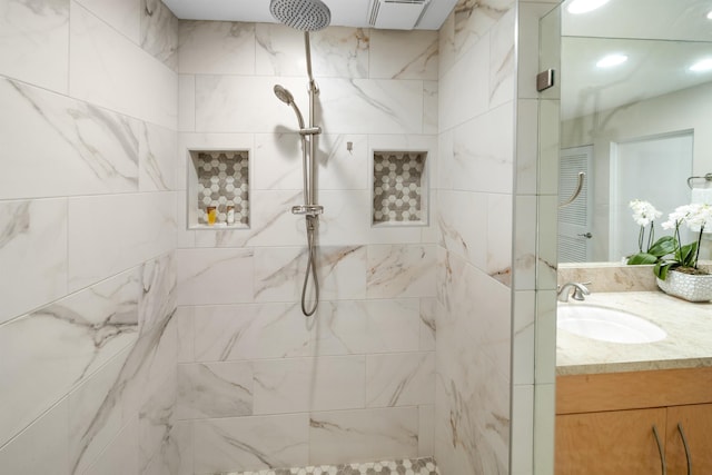 bathroom with tiled shower and vanity