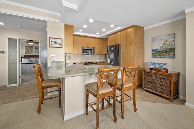 kitchen featuring sink, a breakfast bar, stainless steel appliances, tasteful backsplash, and kitchen peninsula