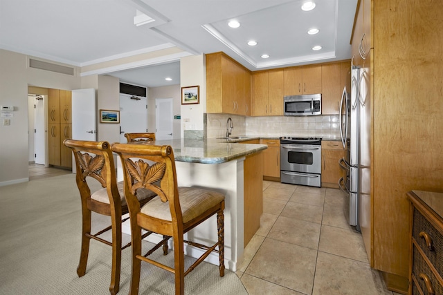 kitchen with sink, light tile patterned floors, stainless steel appliances, decorative backsplash, and kitchen peninsula