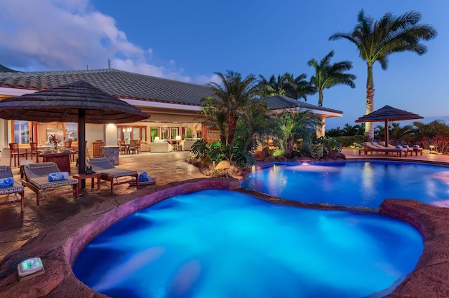 pool at dusk featuring a patio