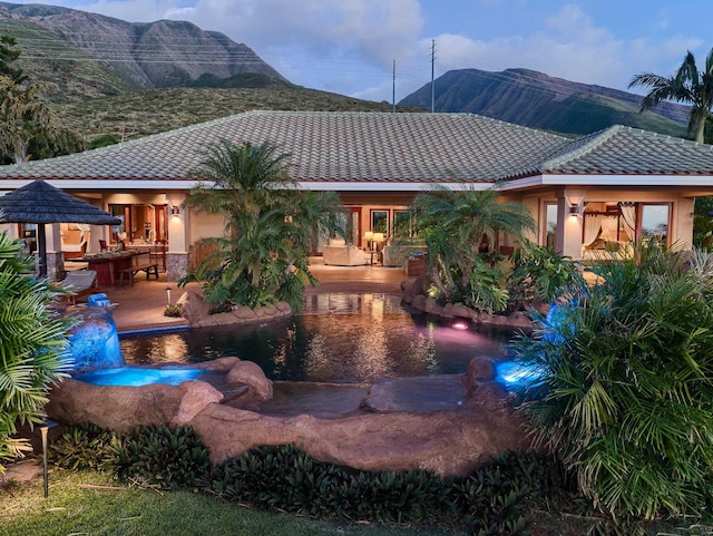 back of property with a mountain view and a patio