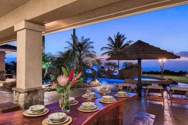 patio terrace at dusk featuring a jacuzzi