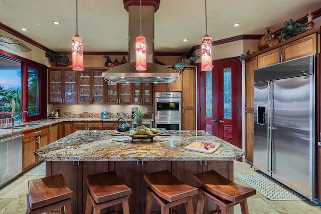 kitchen featuring island exhaust hood, stainless steel appliances, decorative light fixtures, and sink