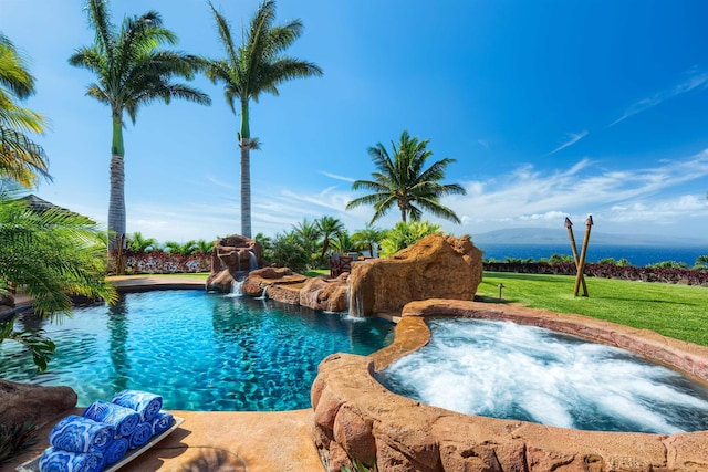 view of swimming pool featuring pool water feature, an in ground hot tub, and a lawn