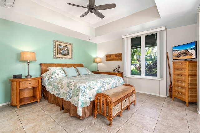 bedroom with tile flooring, ceiling fan, and a tray ceiling