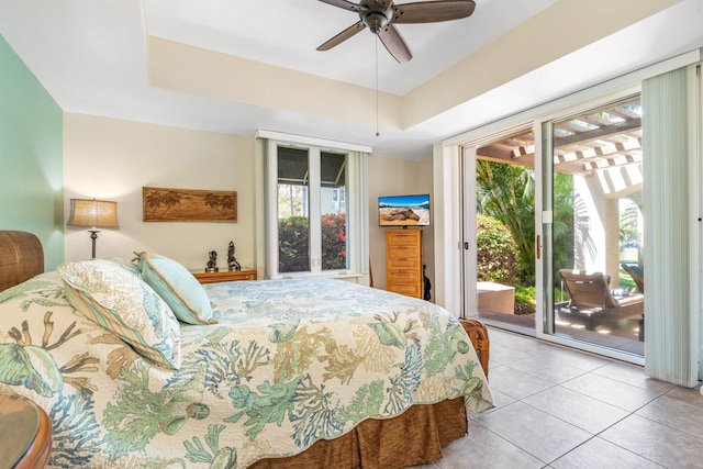 bedroom featuring a raised ceiling, ceiling fan, light tile flooring, and access to exterior