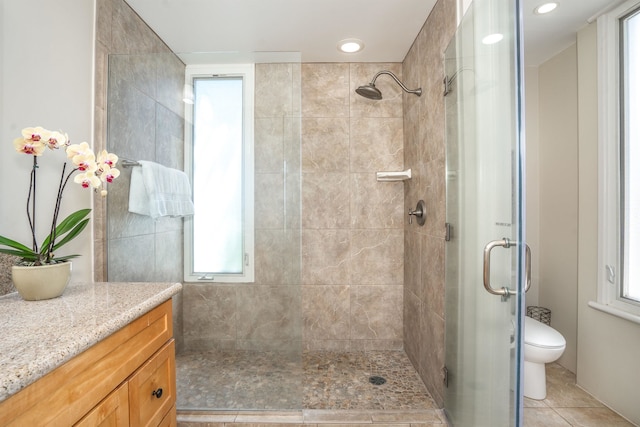 bathroom with a shower with shower door, toilet, tile floors, and vanity