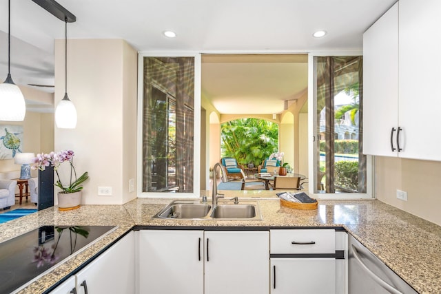 kitchen featuring decorative light fixtures, black electric stovetop, white cabinetry, sink, and dishwasher