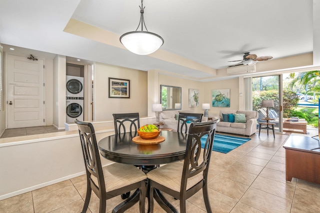 dining room with a healthy amount of sunlight, stacked washer / dryer, ceiling fan, and light tile floors