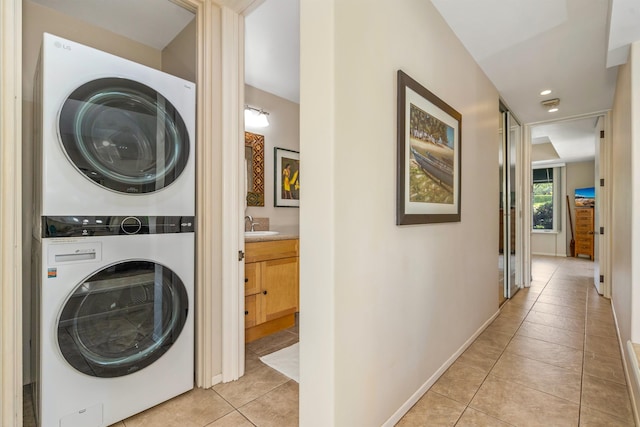 laundry area with sink, light tile flooring, and stacked washer / drying machine