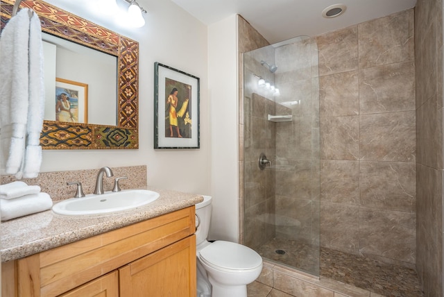 bathroom with tile floors, vanity, toilet, and a shower with shower door