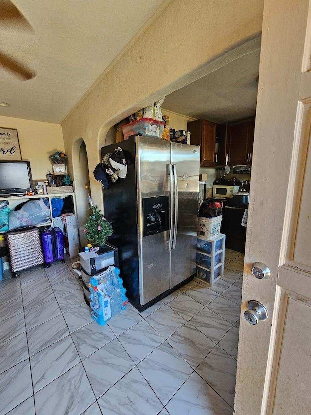 kitchen featuring stainless steel fridge with ice dispenser, dark brown cabinetry, and ceiling fan