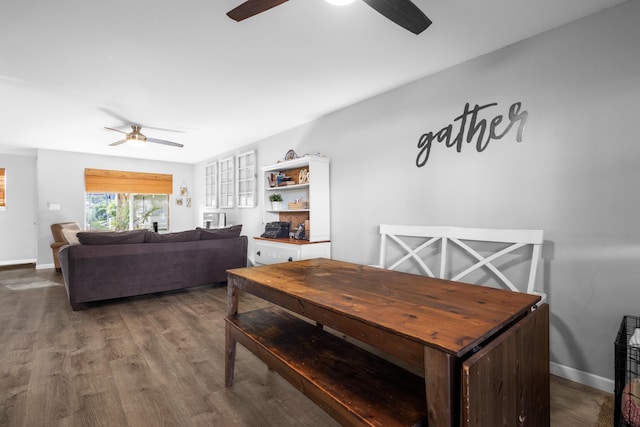 dining area featuring dark wood-style floors, a ceiling fan, and baseboards