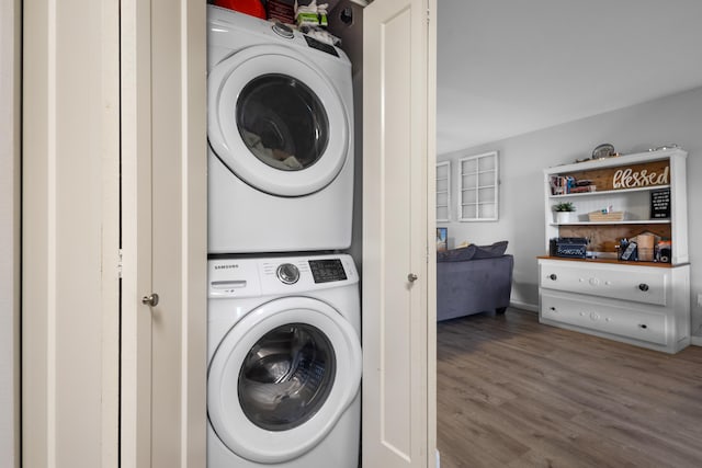 laundry room featuring laundry area, stacked washing maching and dryer, and wood finished floors