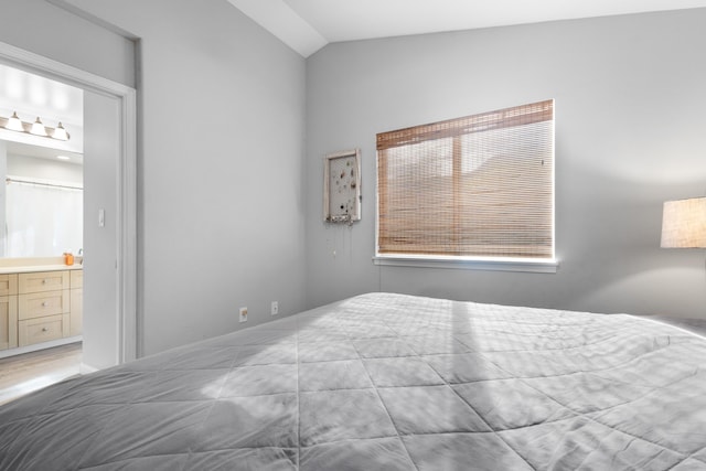 bedroom featuring lofted ceiling and connected bathroom