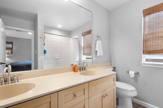 bathroom with baseboards, a sink, toilet, and double vanity