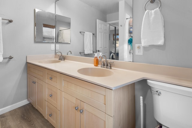 full bathroom with double vanity, a sink, baseboards, and wood finished floors