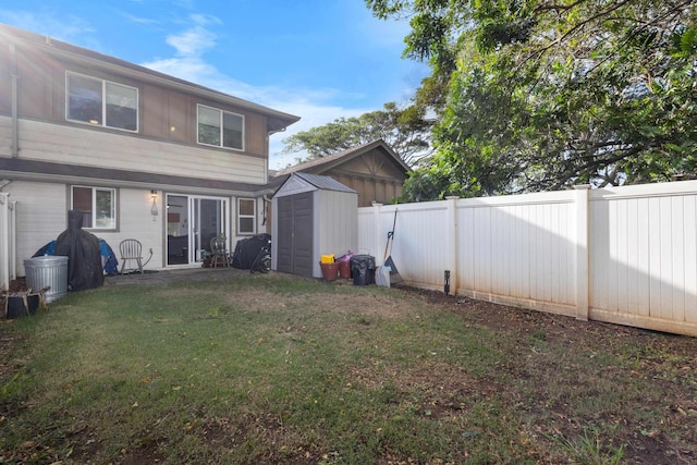 rear view of property with a yard, a storage unit, an outdoor structure, and a fenced backyard