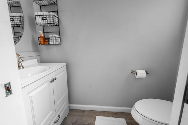 bathroom with toilet, baseboards, wood finished floors, and vanity