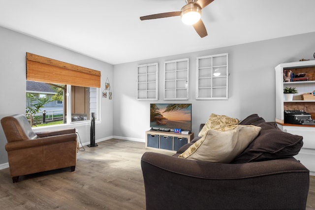 living room with ceiling fan, baseboards, and wood finished floors