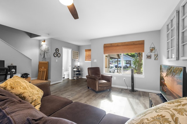 living area featuring wood finished floors, a ceiling fan, and baseboards