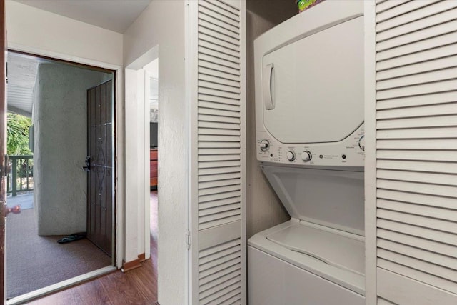 laundry room featuring stacked washer and dryer and dark wood-type flooring