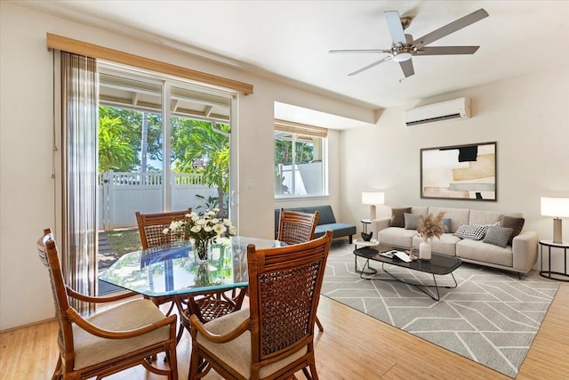 dining area featuring an AC wall unit, wood-type flooring, and ceiling fan