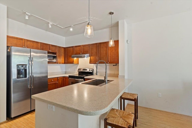 kitchen with a kitchen breakfast bar, light hardwood / wood-style floors, kitchen peninsula, and appliances with stainless steel finishes