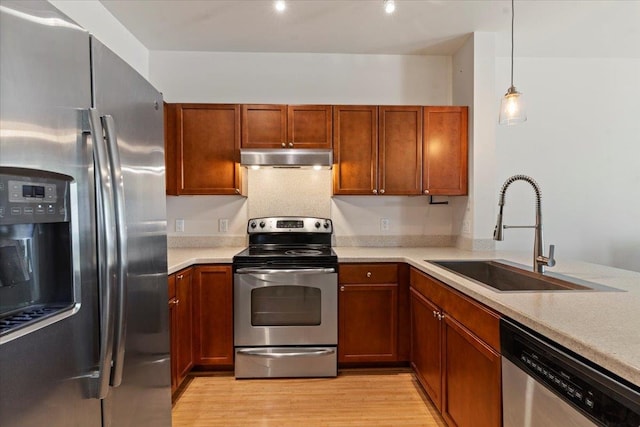 kitchen with pendant lighting, light hardwood / wood-style floors, appliances with stainless steel finishes, and sink